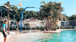 A swimming pool with clear water, palm trees, and a water feature.