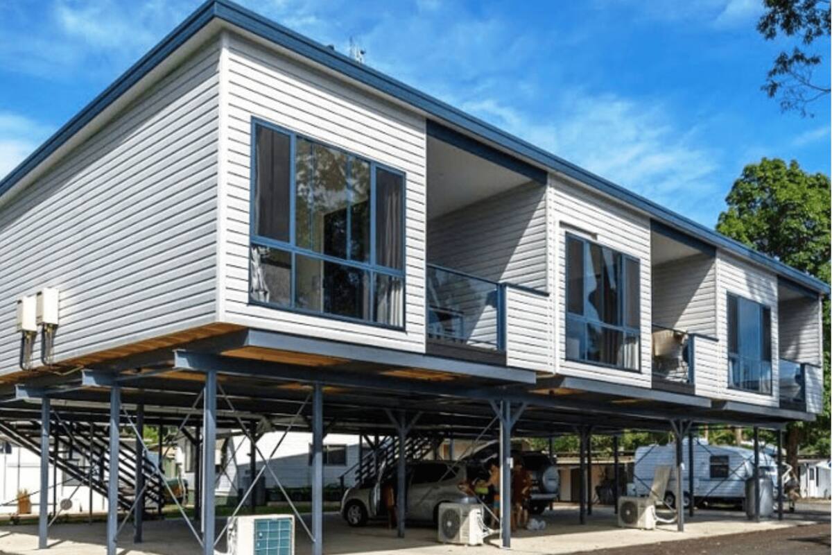 Et toetagers hus med en overdækket garage, store vinduer og en trappe, der fører op til etageplan.