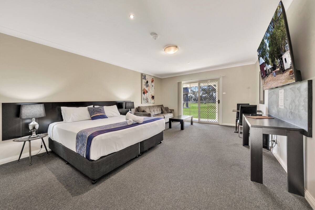 A modern hotel room with a large bed, a desk, and a view of the outdoors.