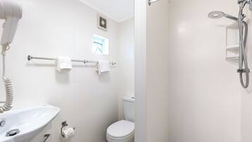 A bathroom with a sink, toilet, towel rack, and a shower area.