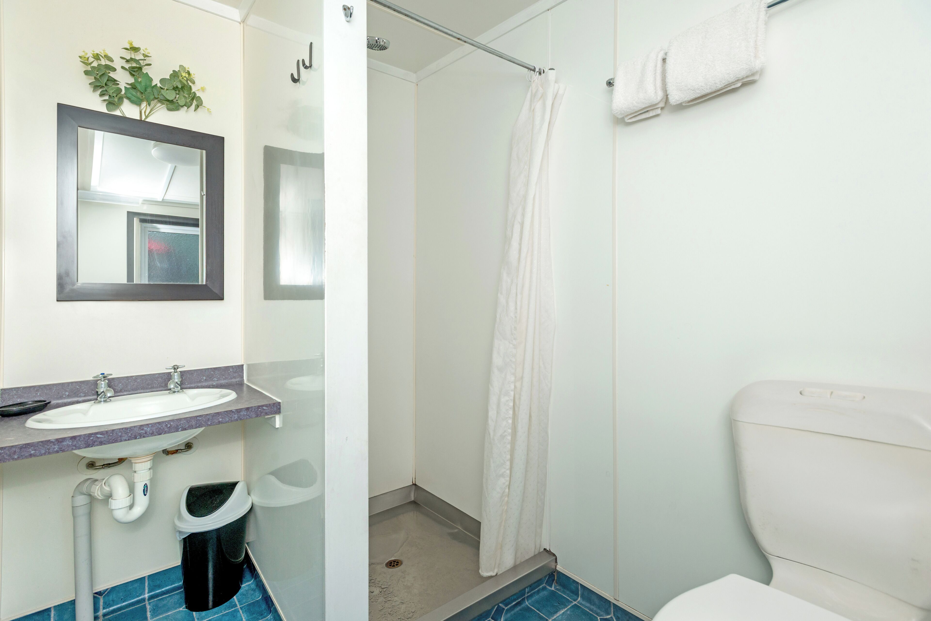 A bathroom with a sink, mirror, shower, and toilet.