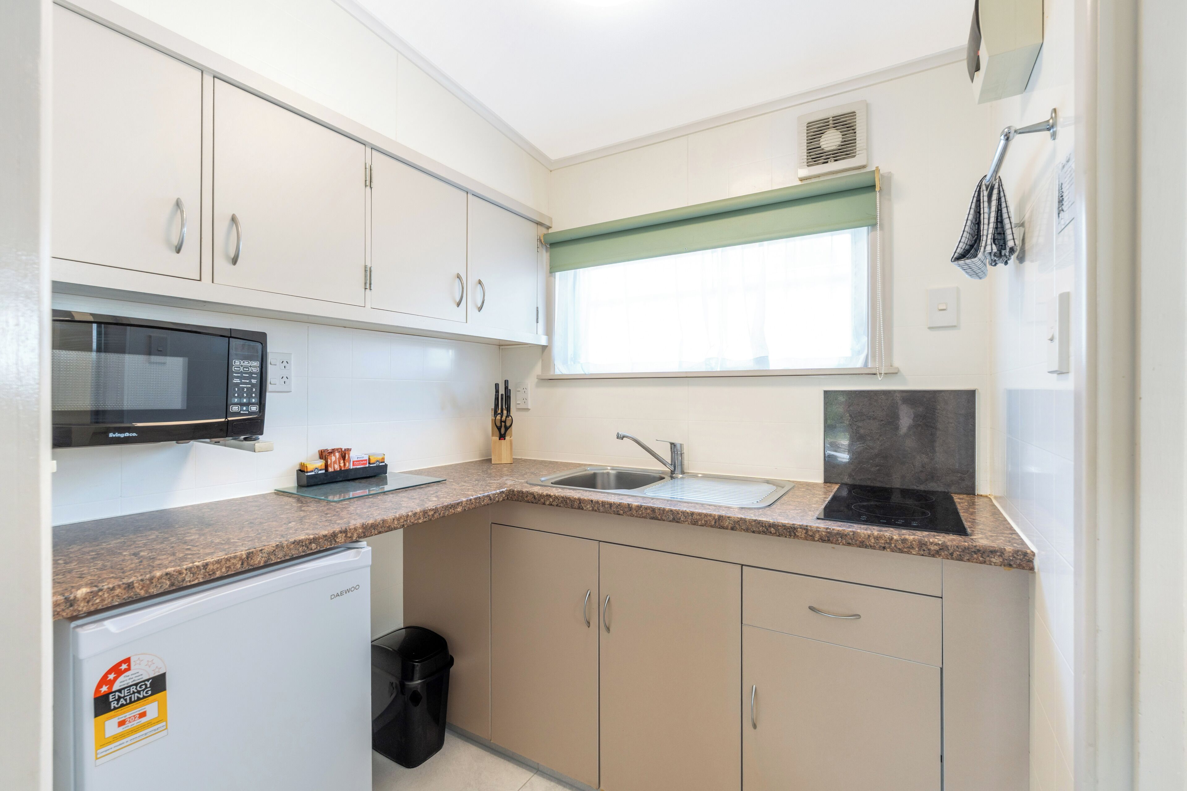 Una cocina compacta equipada con microondas, fregadero y un refrigerador pequeño.