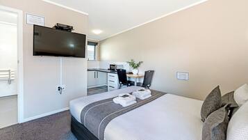 A hotel room with a bed, a desk, a television, and a small kitchenette.