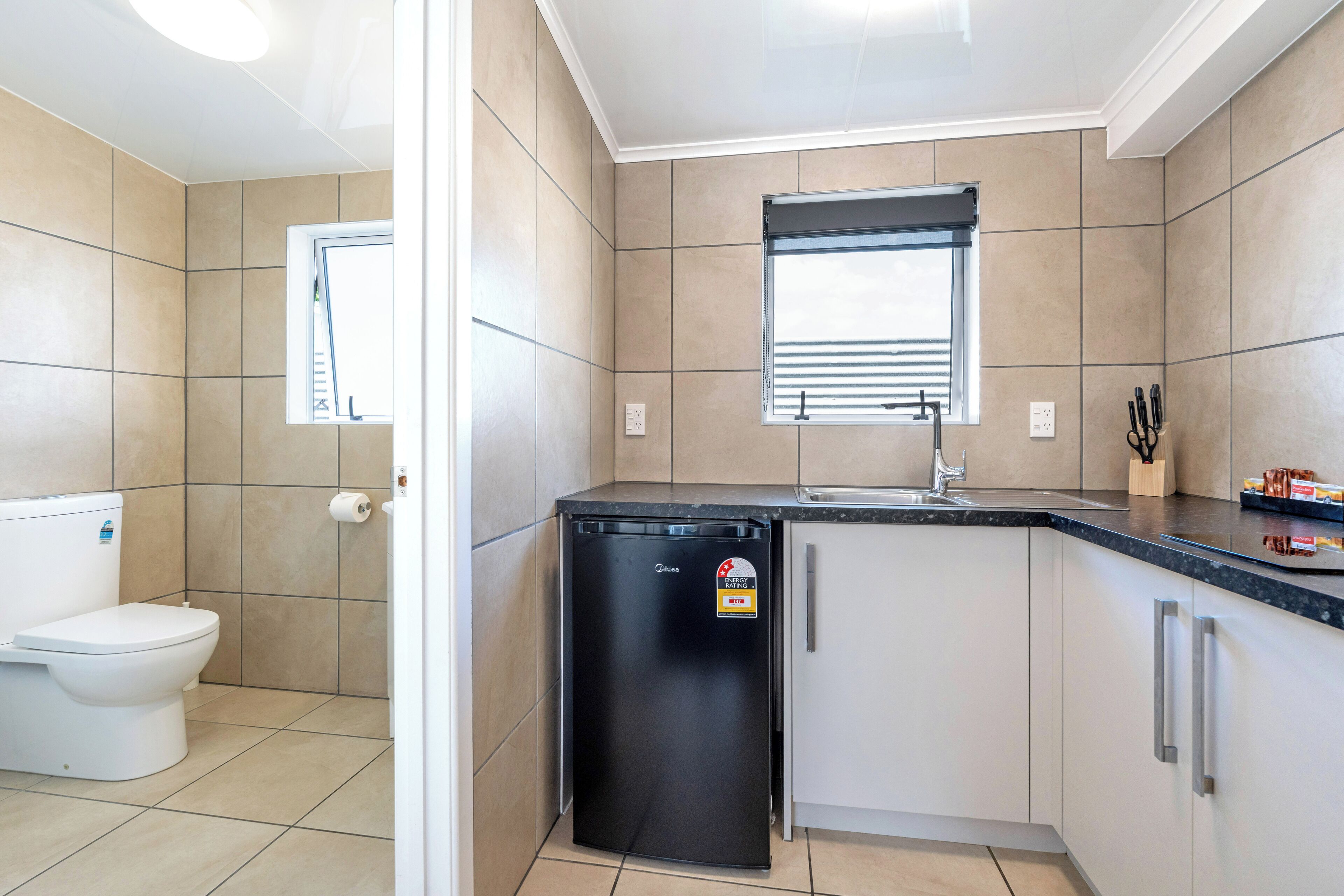 A compact kitchen with a refrigerator, sink, and window.