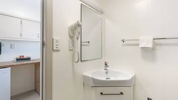 A bathroom with a white sink, a mirror, a towel rack, and a hairdryer.