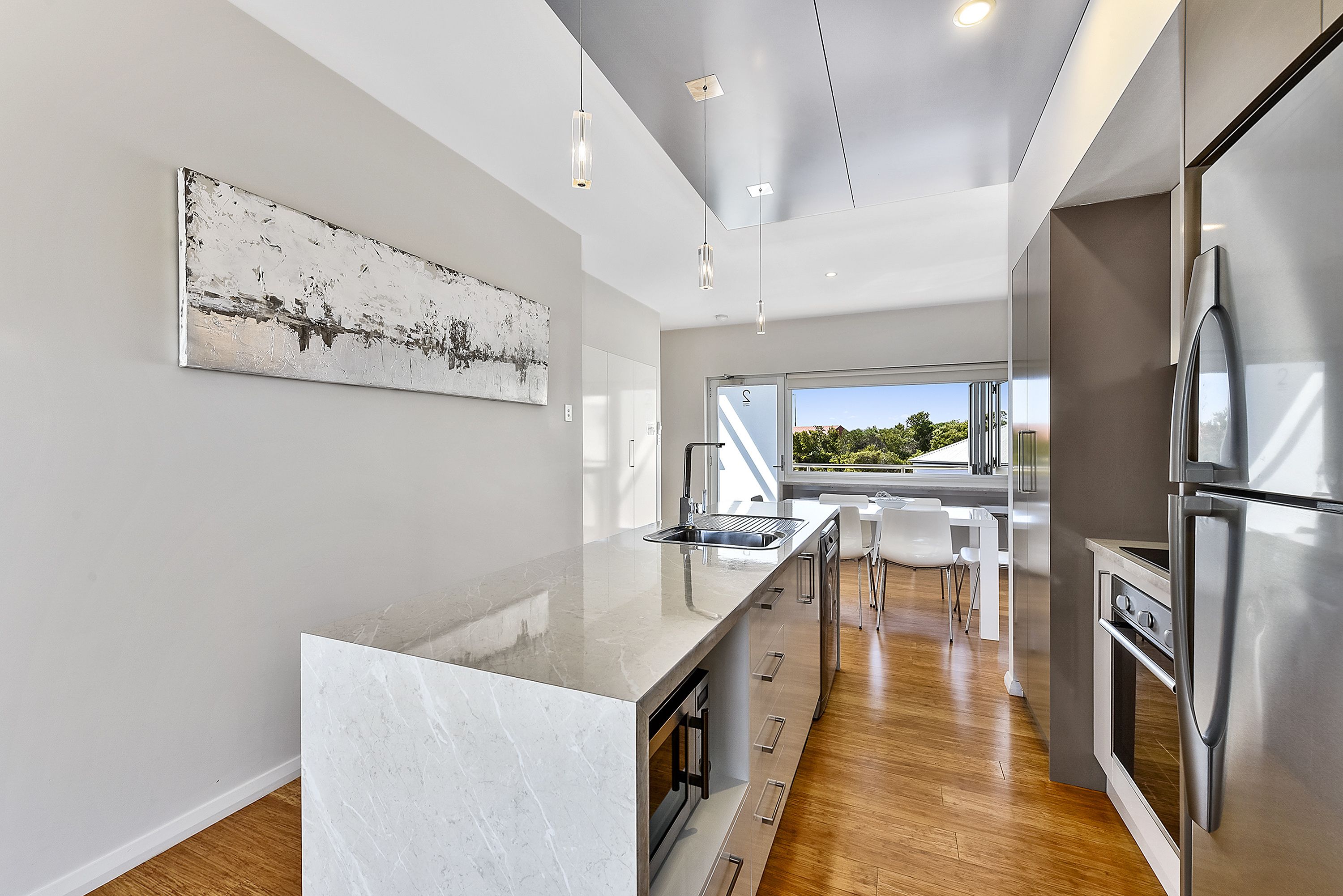 A modern kitchen with a large island, stainless steel appliances, and a view to the outdoors.