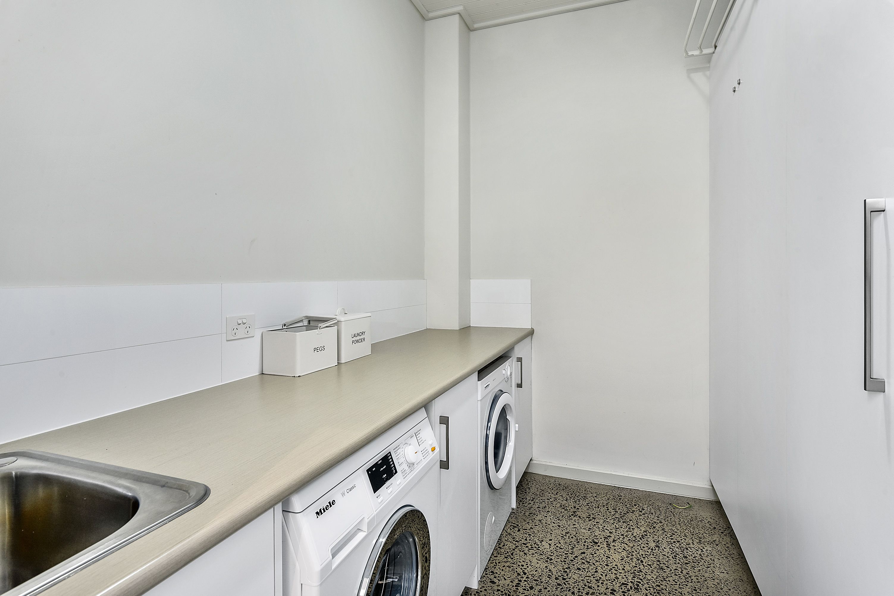 Een kleine wasruimte met een wasmachine, een droger en een wasbak.