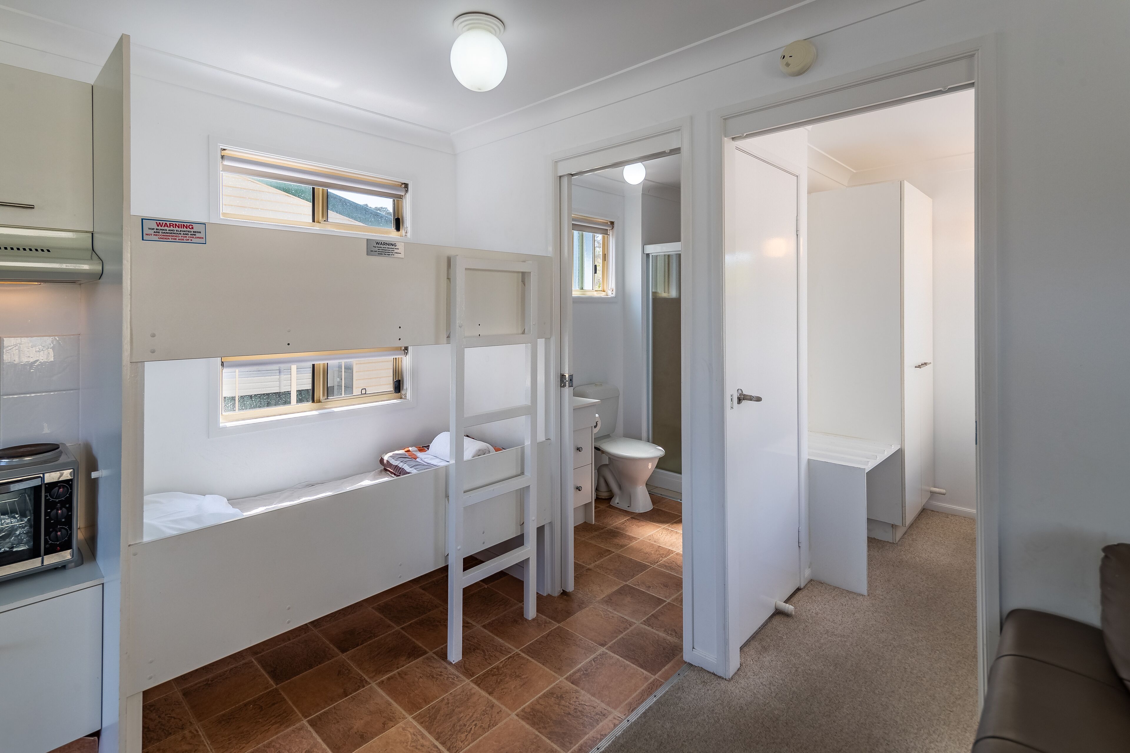 A compact hotel room with a kitchenette, a small bathroom, and a view of the outside.