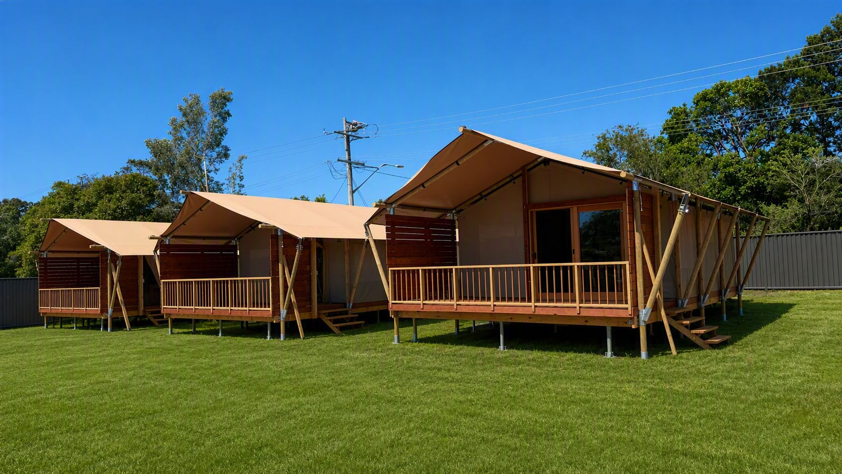 Filas de cabañas de madera con porches adosados, ubicadas en un campo cubierto de césped.