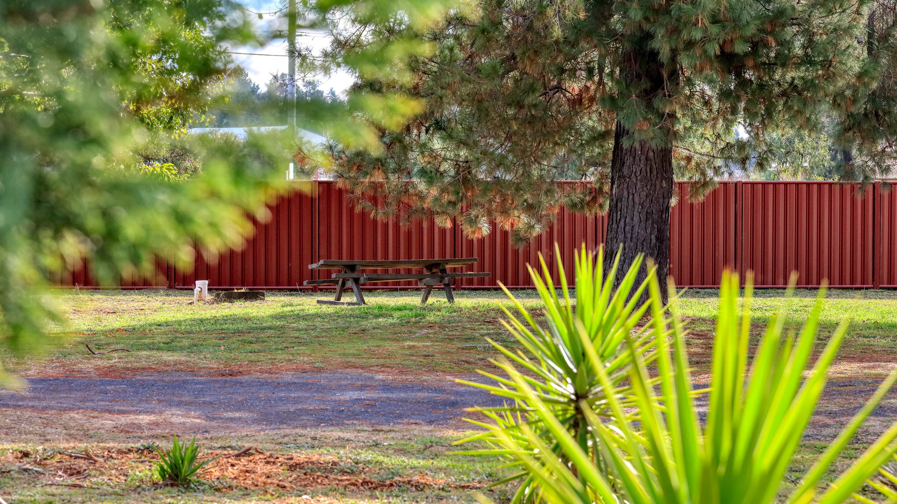 Una mesa de picnic y una cerca roja en un área con césped.