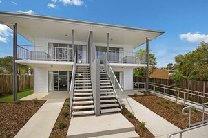 A modern two-story house with a central staircase, a covered balcony, and a fenced backyard.