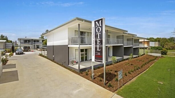 A modern motel with a prominent sign, a covered outdoor area, and a well-maintained lawn. - Cooroy Luxury Motel Apartments Noosa (Cooroy)