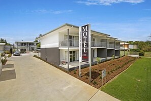 A modern motel with a prominent sign, a covered outdoor area, and a well-maintained lawn. - Cooroy Luxury Motel Apartments Noosa (Cooroy)