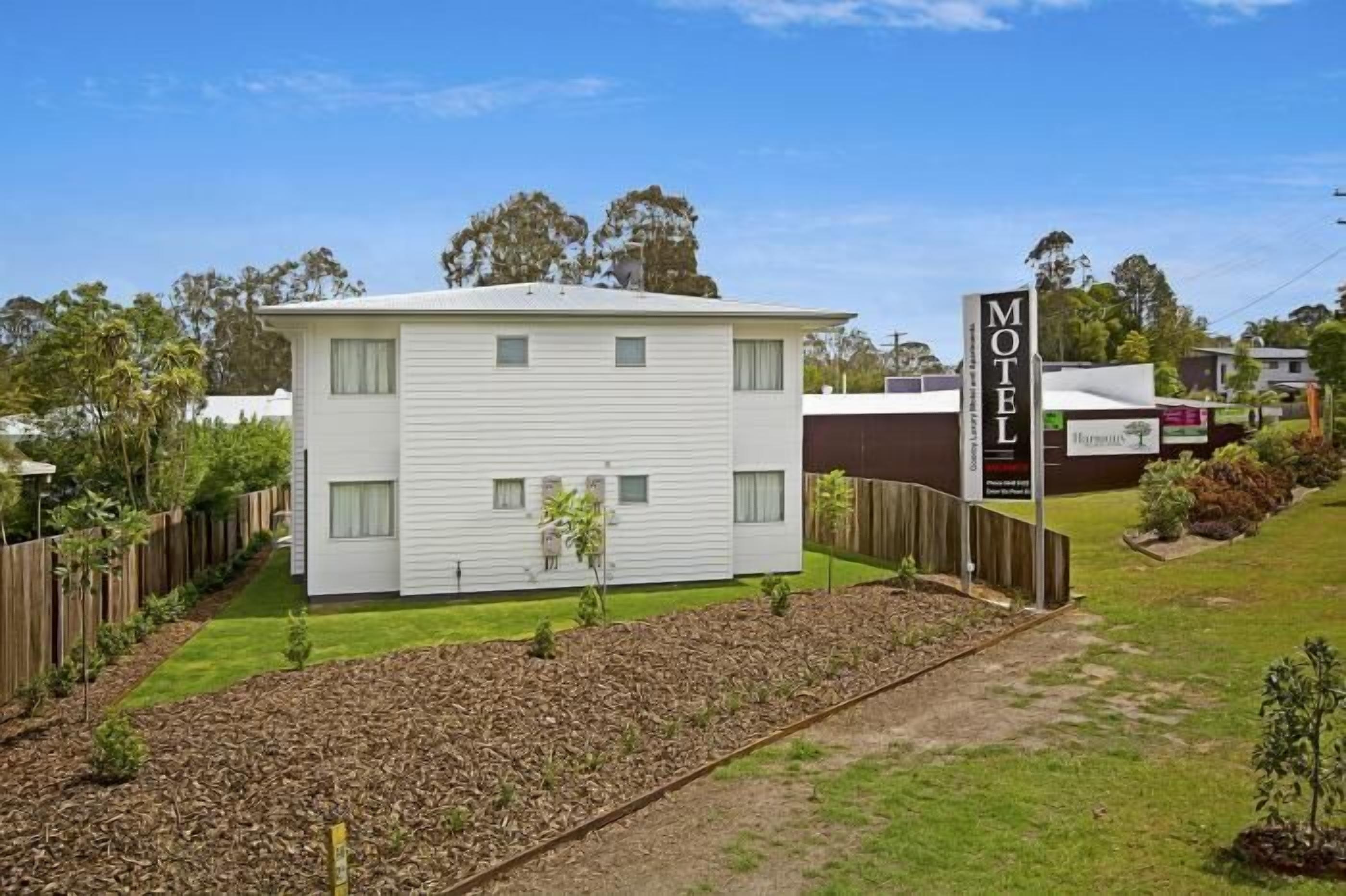 A motel with a white exterior, a signboard, and a well-maintained lawn.