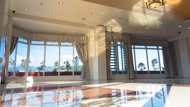 A spacious room with large windows, a chandelier, and a reflective floor. - Baguio City Center Hotel (Baguio)
