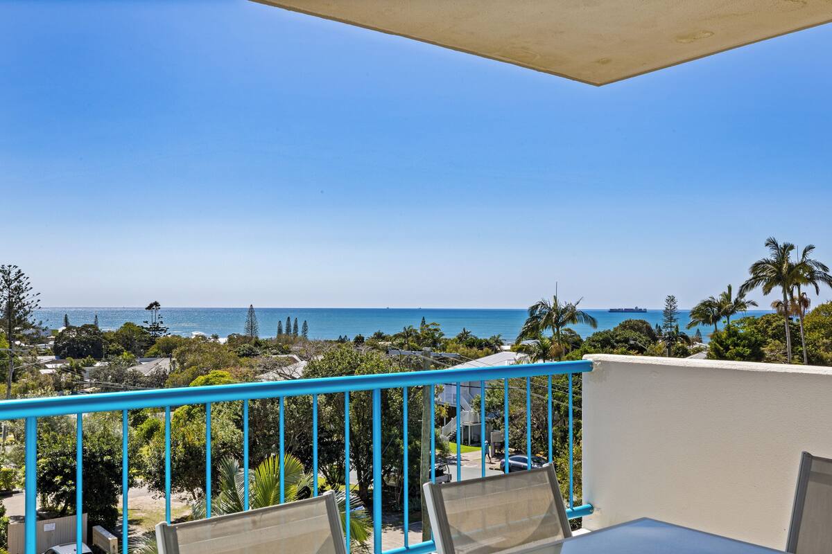 Een balkon met uitzicht op de oceaan en palmbomen.