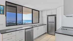 Une cuisine moderne dotée d’une grande fenêtre, d’appareils électroménagers en acier inoxydable et offrant une vue sur la mer.