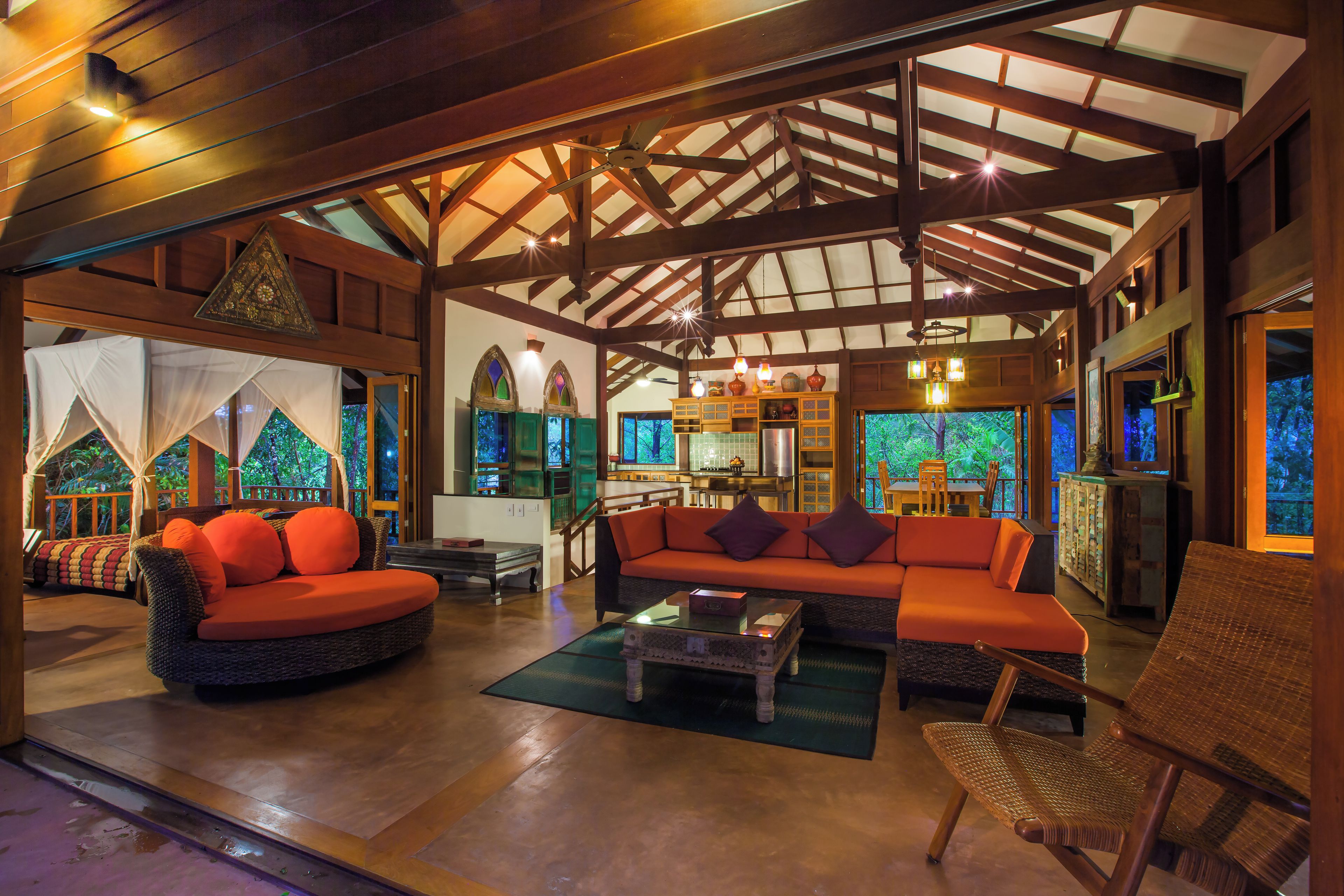 A spacious indoor area with a high ceiling, wooden beams, a sofa, a chair, and a table.