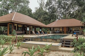 Un espace aménagé au bord de la piscine, avec des chaises longues, une piscine et un coin salon abrité.