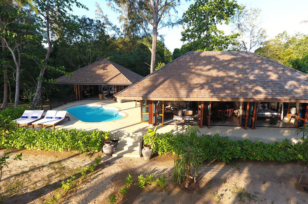 A resort with a swimming pool, lounge chairs, and a covered outdoor area.