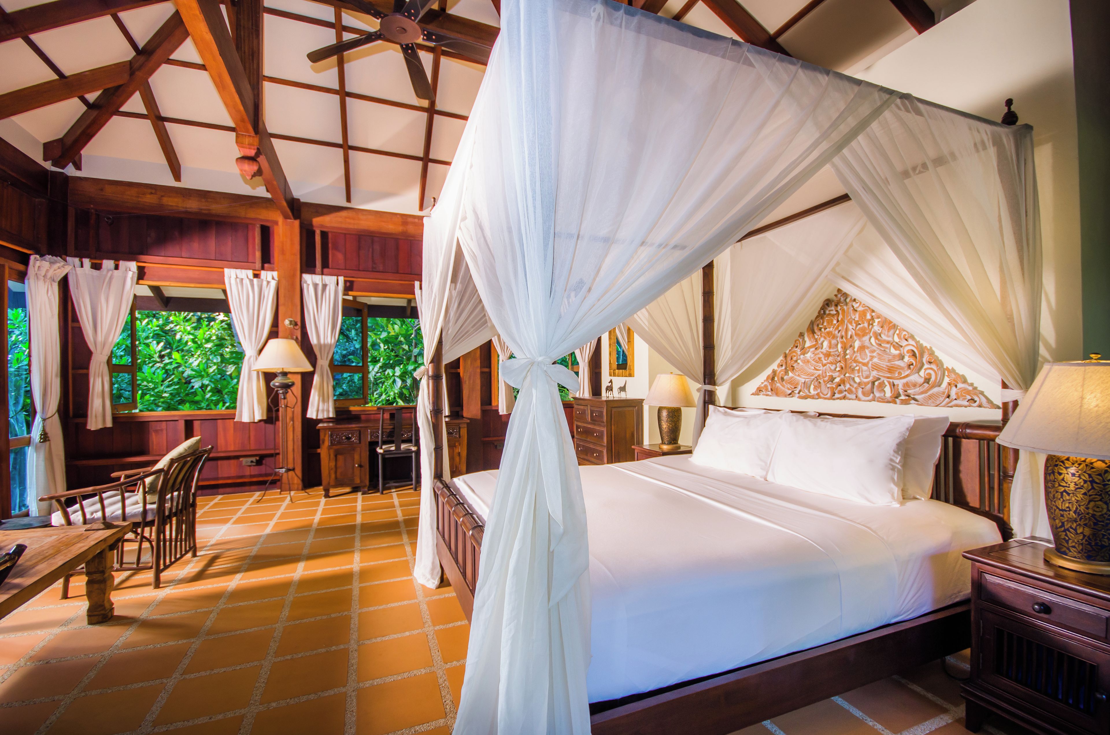 A room with a four-poster bed, wooden furniture, and a tiled floor.