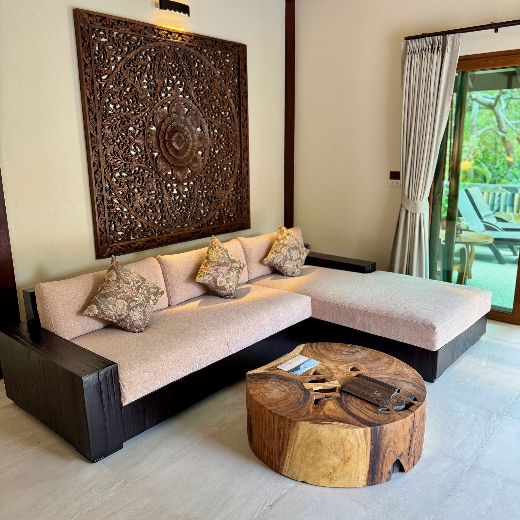 A modern living room with a sectional sofa, a decorative wall panel, and a round wooden coffee table.
