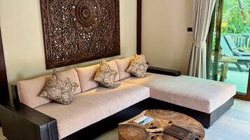 A modern living room with a sectional sofa, a decorative wall panel, and a round wooden coffee table.