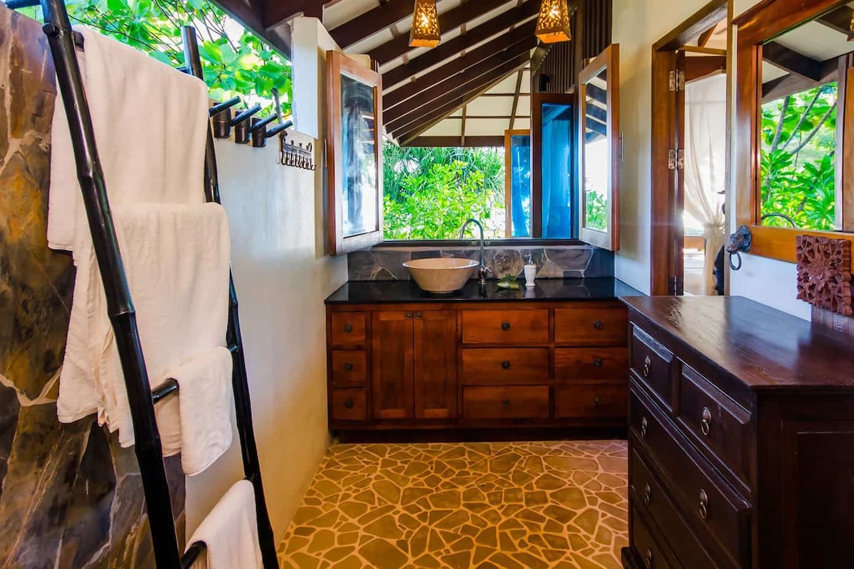 Une salle de bain avec un mur en pierre, des meubles en bois, un lavabo et un porte-serviettes.
