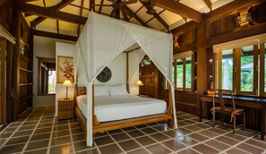 Een hemelbed met baldakijn, houten vloer, een bureau met stoelen en een raam met uitzicht.
