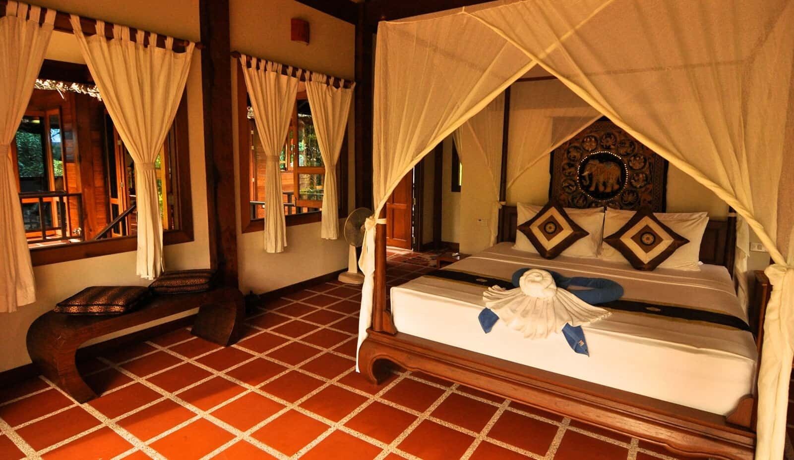 A room with a bed, a bench, and a fan.