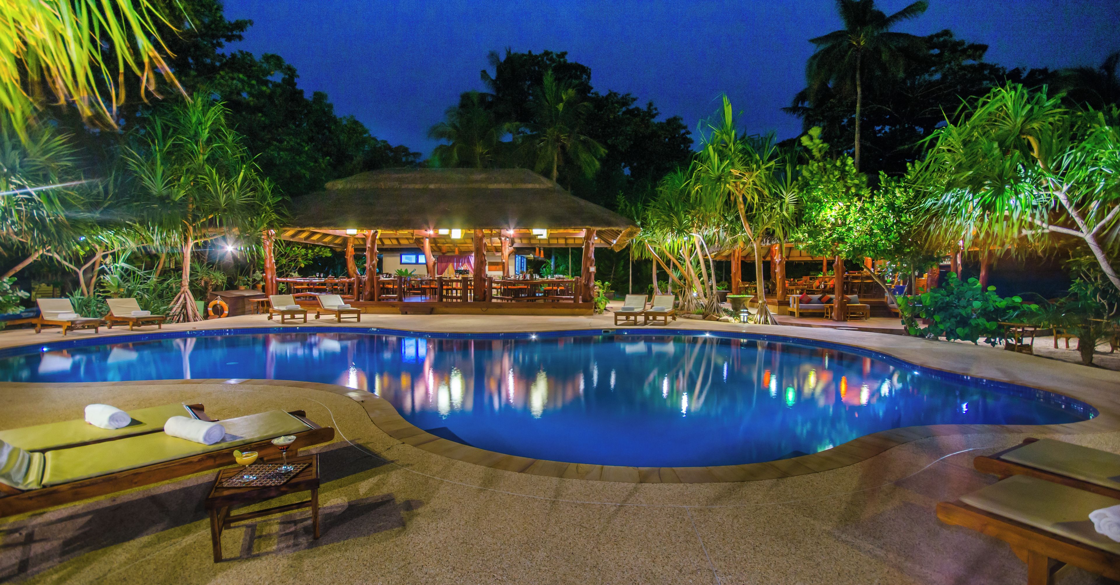 A swimming pool with lounge chairs and a covered seating area.