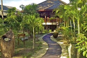 Un complexe hôtelier tropical doté d’une passerelle en bois menant à un bâtiment avec un balcon.