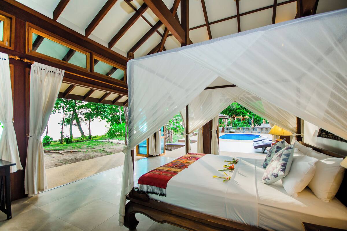 Une chambre avec un lit, une vue sur une piscine et un espace extérieur couvert.