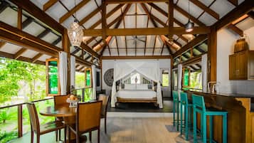 A bedroom with a canopy bed, a dining area with a table and chairs, and a kitchen area with bar stools.