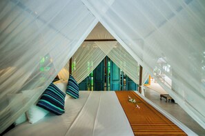 A tent-style room with a bed, pillows, and a small table.
