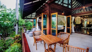 Une terrasse en bois avec une table et des chaises, entourée d’une végétation luxuriante.