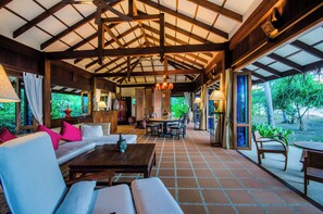 Un vaste espace intérieur doté d’un haut plafond, de poutres en bois et d’un assortiment de différents types de sièges, notamment des canapés et des fauteuils.
