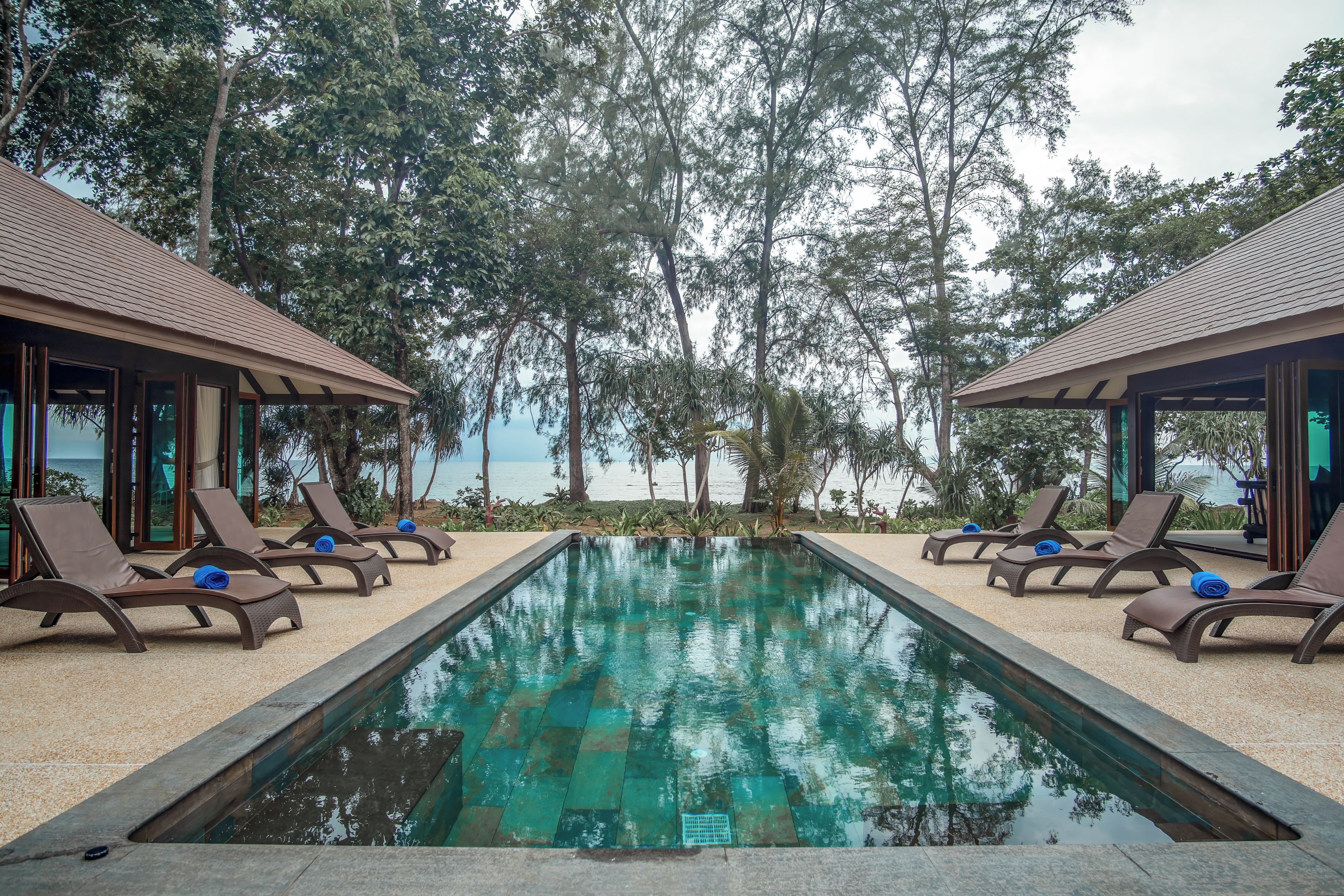 A swimming pool with lounge chairs and a view of the sea.