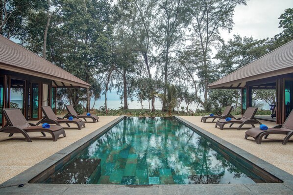 A swimming pool with lounge chairs and a view of the sea.