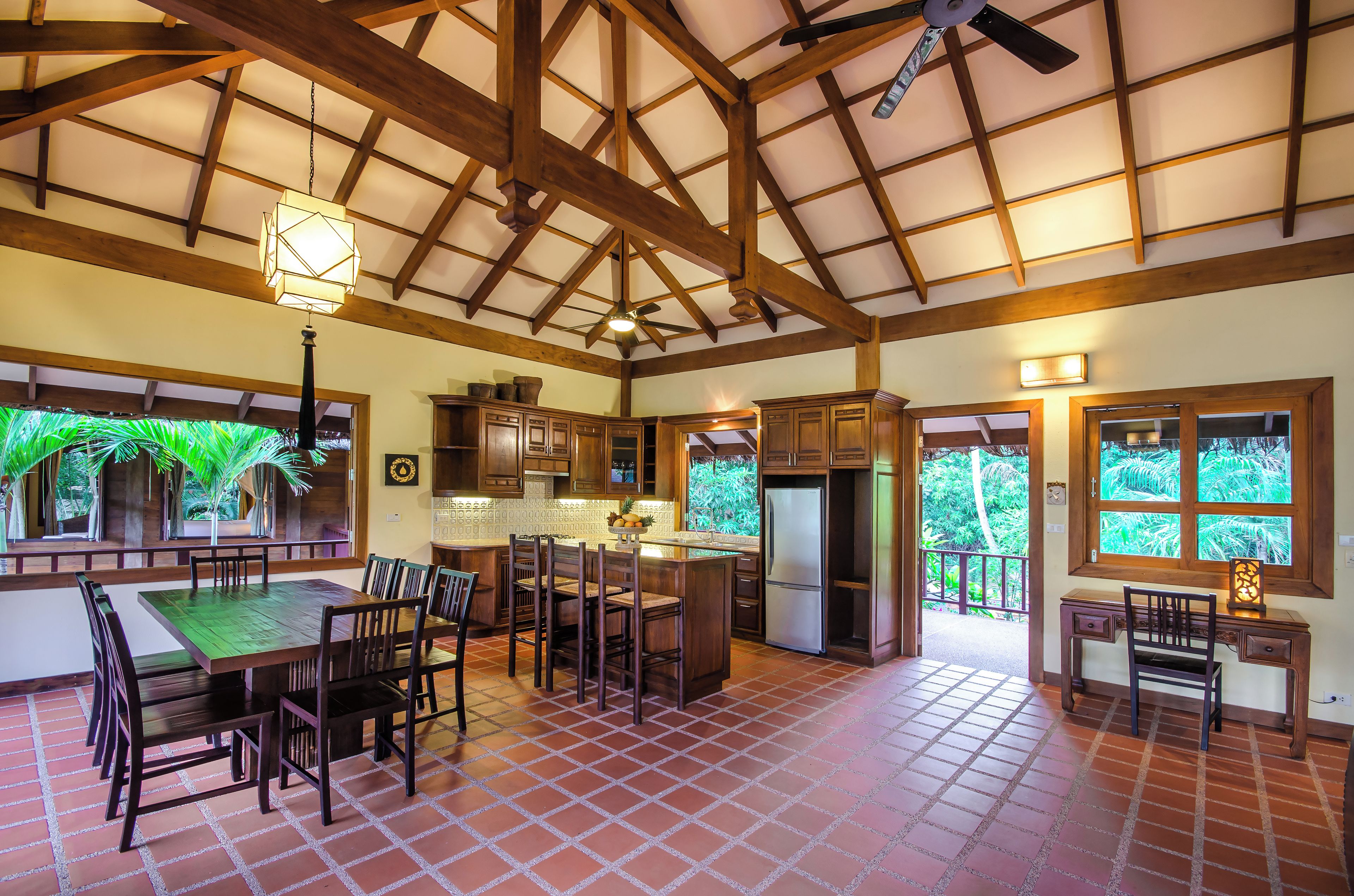 Una cocina amplia con vigas de madera, un comedor con una mesa grande y sillas, y vistas a zonas verdes.