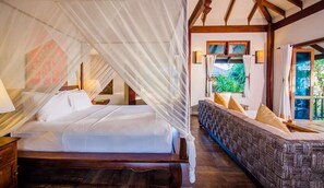 Une chambre à coucher avec un lit à baldaquin, un canapé avec des coussins, une fenêtre donnant sur un paysage verdoyant et une structure de plafond en bois.