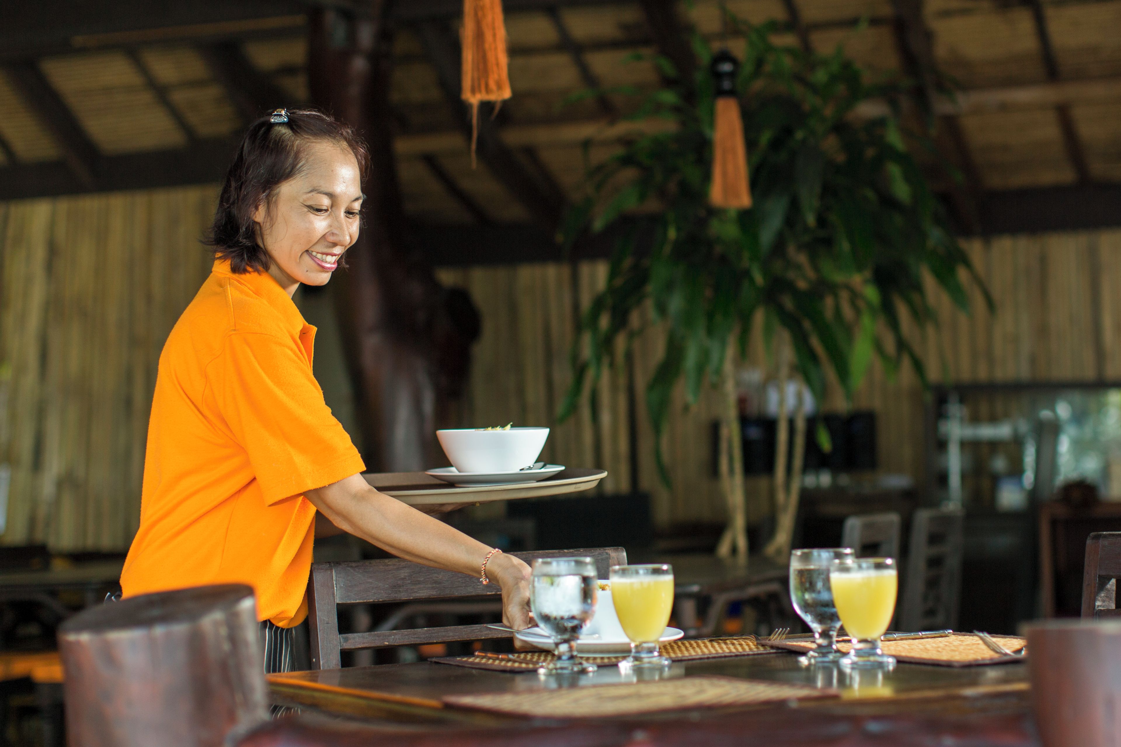 A person serving drinks at a table with a bowl and a glass of juice.