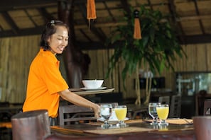 A person serving drinks at a table with a bowl and a glass of juice.