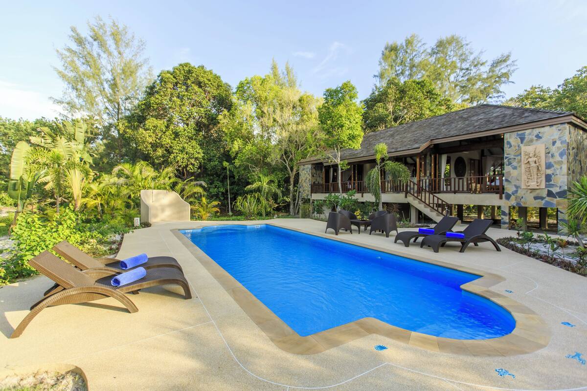 Une piscine avec des chaises longues et un bâtiment doté d’une façade en pierre.