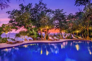 A poolside area with lounge chairs and a view of the ocean at sunset. - Koh Jum Beach Villas (Nuea Khlong)