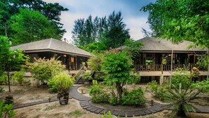 Un complexe hôtelier comprenant deux bâtiments, un sentier bordé de jardins et diverses plantes.