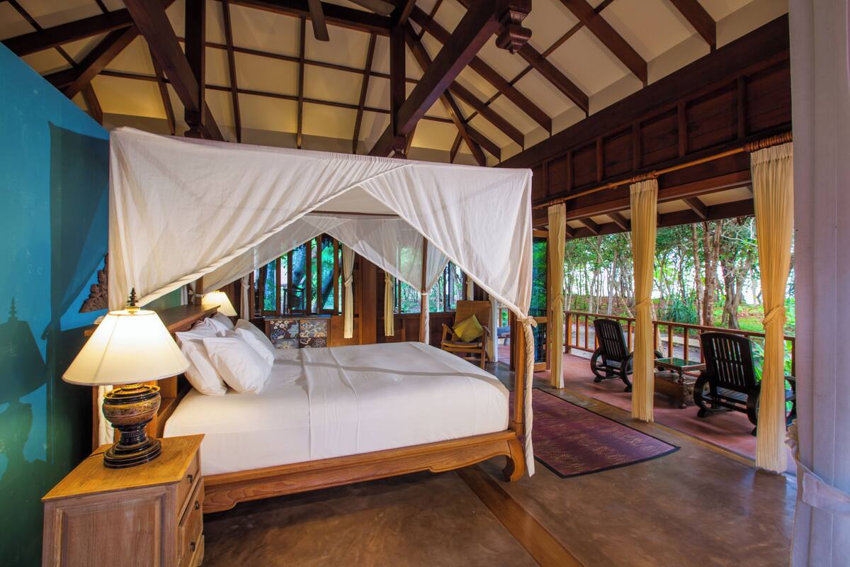 Une chambre à coucher avec un lit à baldaquin, des meubles en bois et une vue sur l’extérieur.