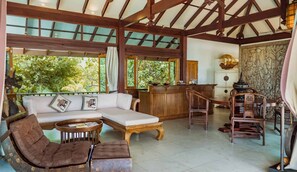 Ein geräumiges Zimmer mit Holzbalkendecke, einer Couch, einem Esstisch und Stühlen.