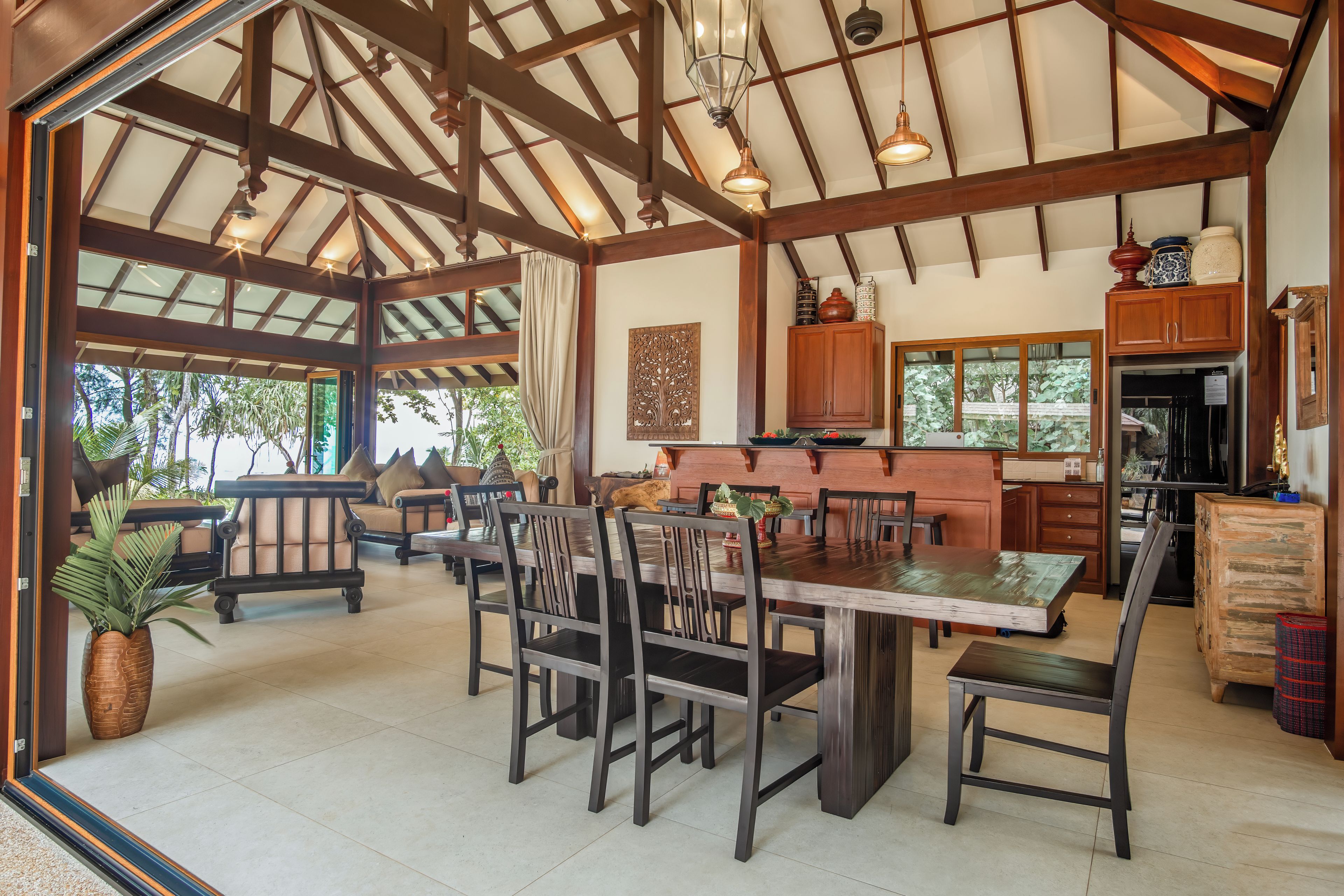 Un comedor amplio con una gran mesa y sillas de madera, una cocina con armarios de madera y un techo con vigas a la vista.
