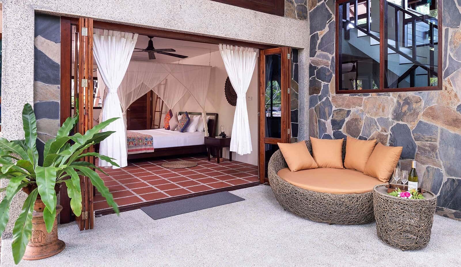 Un dormitorio con una cama, cortinas y una pared de piedra.